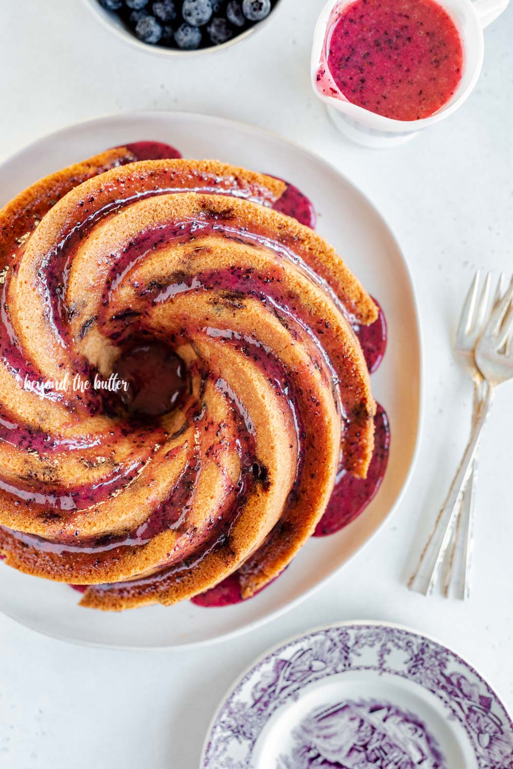 Overhead image of super easy blueberry bundt cake recipe with blueberry glaze drizzled over the top | All Images © Luyiz, LLC