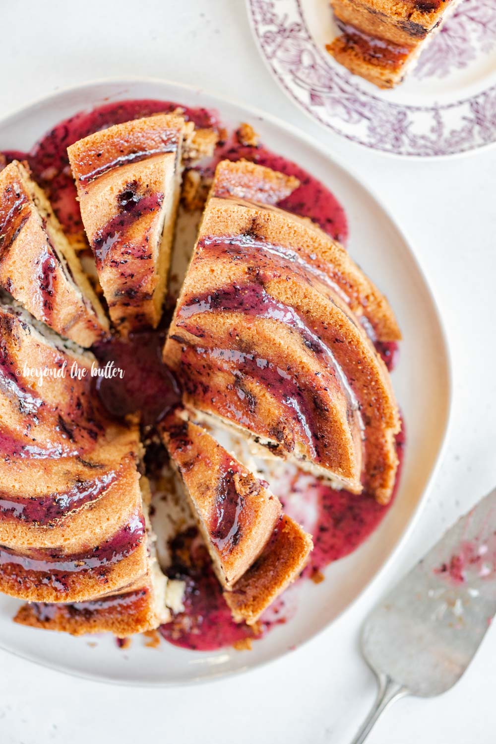 Overhead image of sliced blueberry bundt cake with blueberry glaze drizzled over the top | All Images © Luyiz, LLC