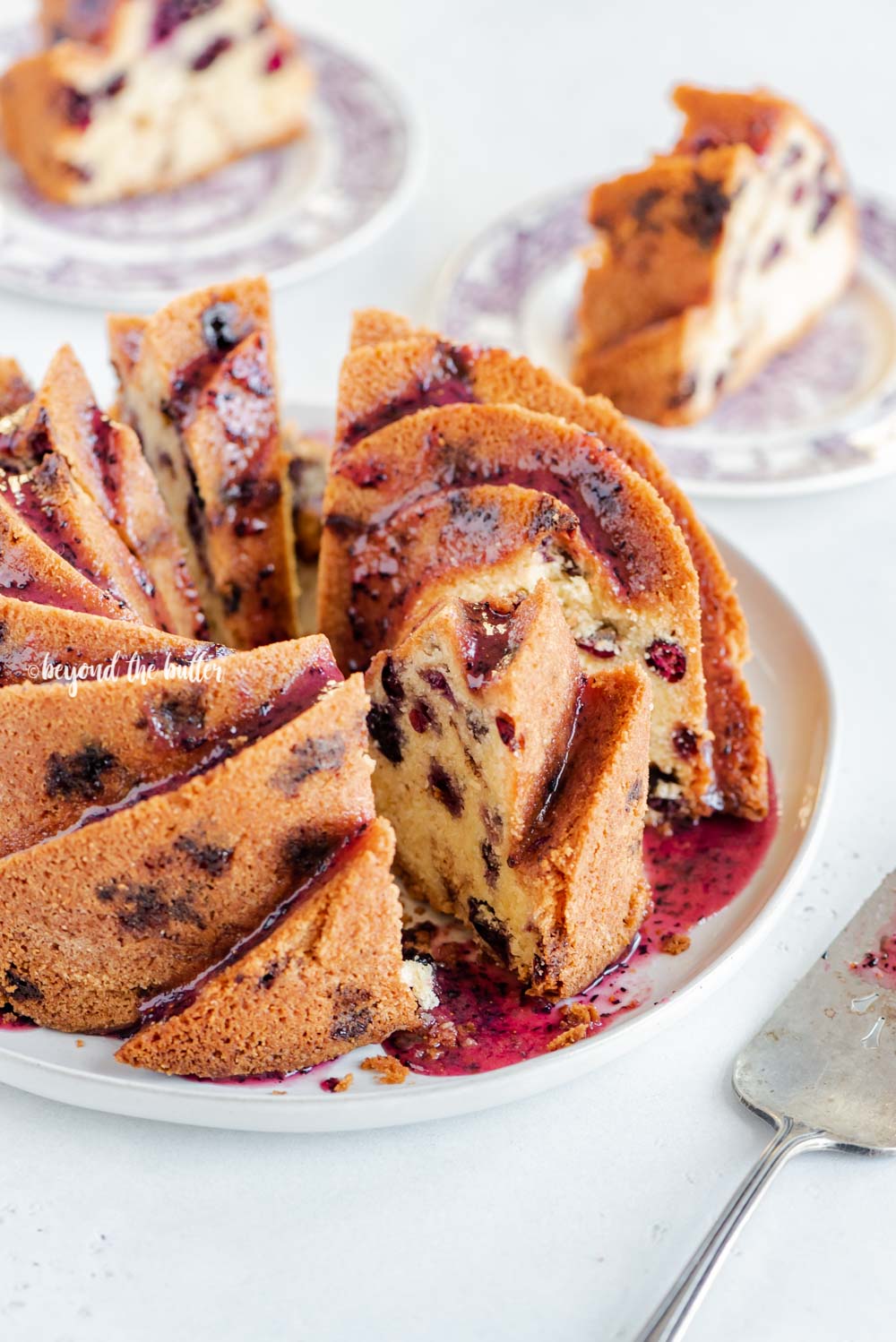 Angled image of sliced blueberry bundt cake with blueberry glaze drizzled over the top | All Images © Luyiz, LLC