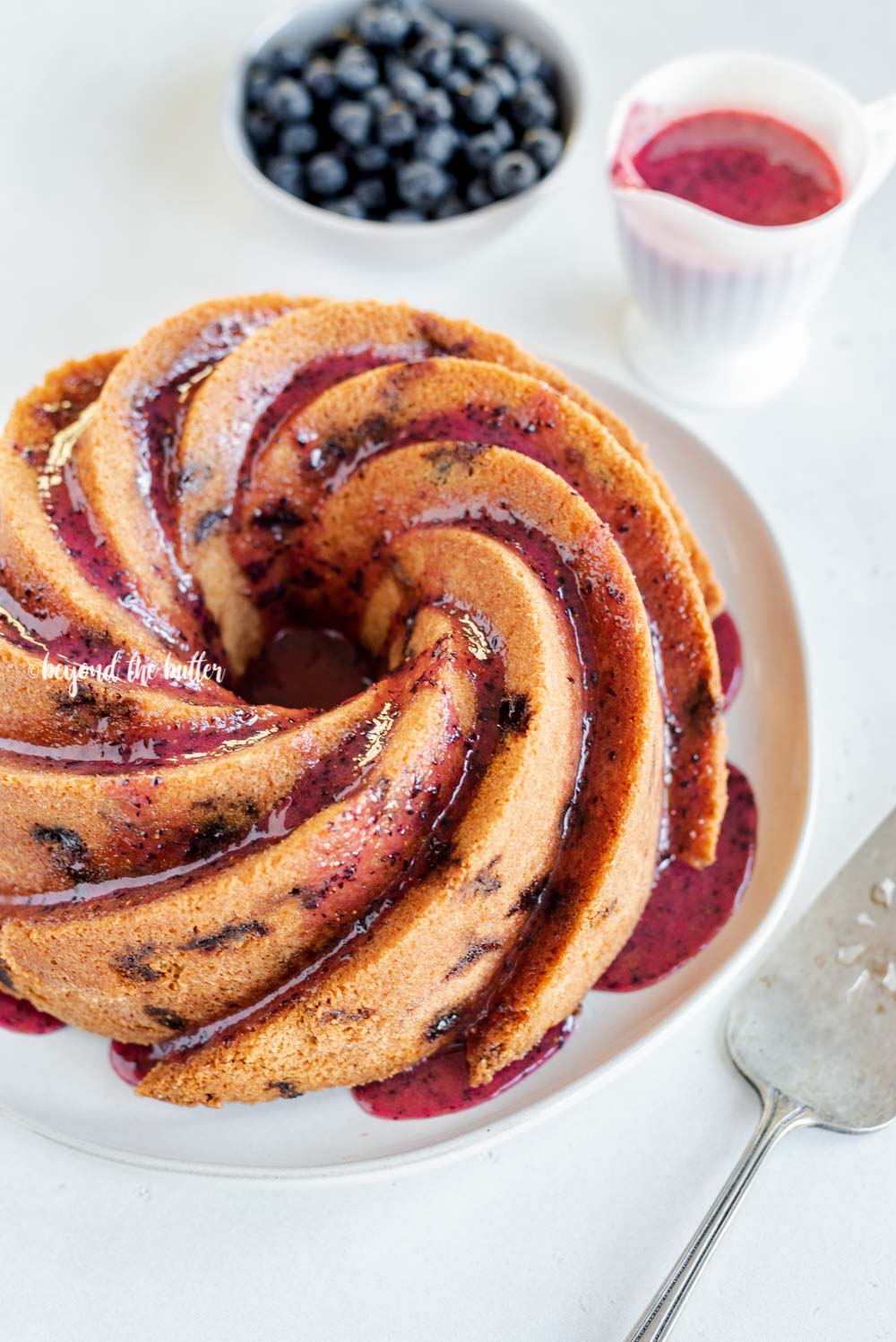 Angled image of super easy blueberry bundt cake with blueberry glaze drizzled over the top | All Images © Luyiz, LLC