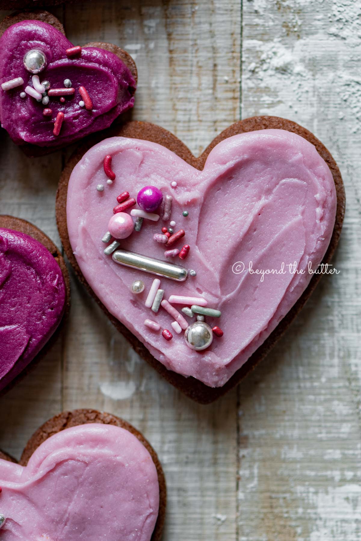 Closeup of decorated chocolate cut out sugar cookies on a light wood colored background | All Images © Luyiz®