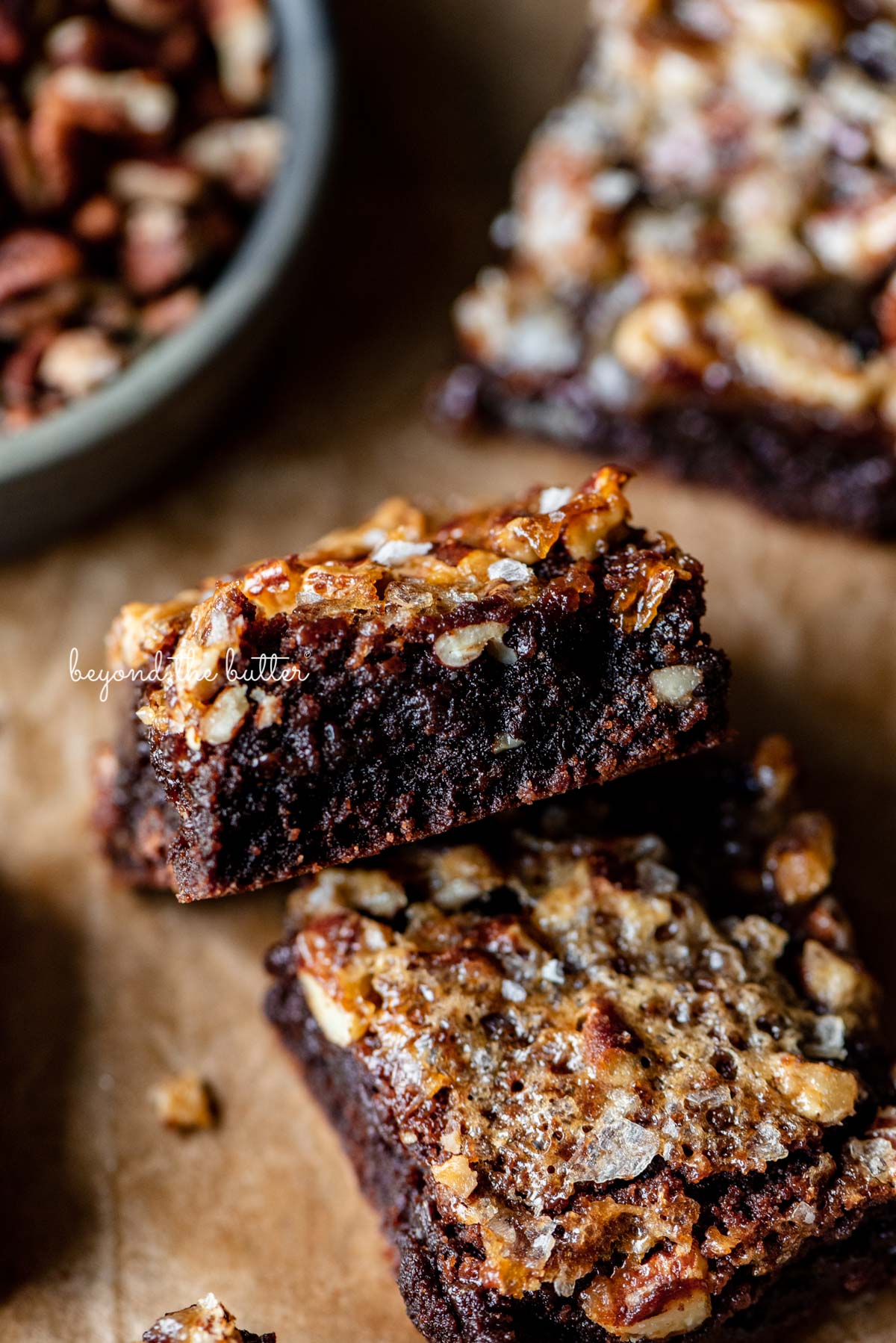 Semi-stacked salted pecan pie brownies on brown parchment paper | © Luyiz®