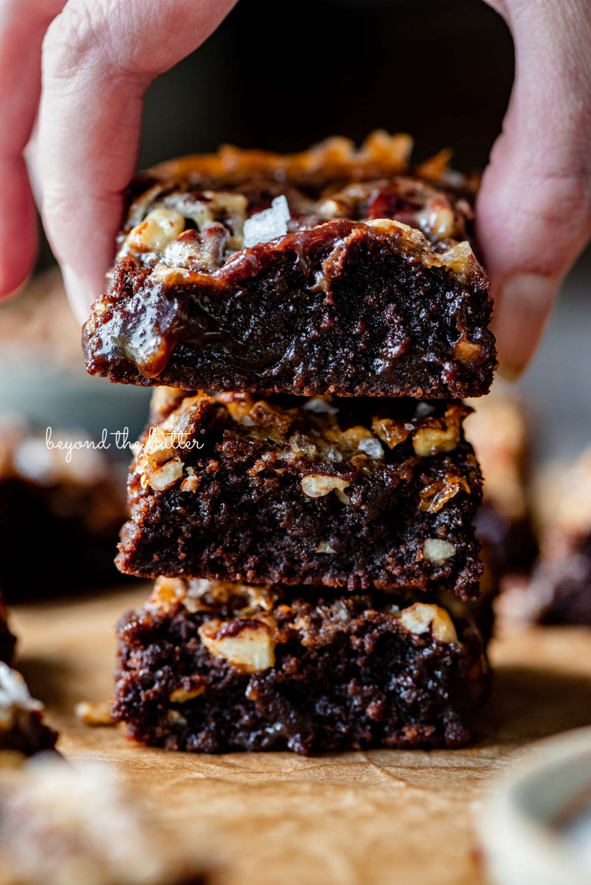 Stacking the best salted pecan pie brownies on brown parchment paper | © Luyiz®