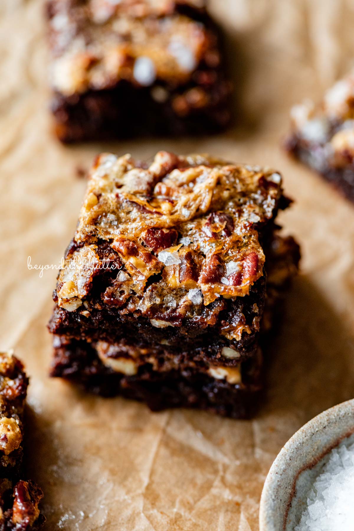 Stacked salted pecan pie brownies on brown parchment paper | © Luyiz®