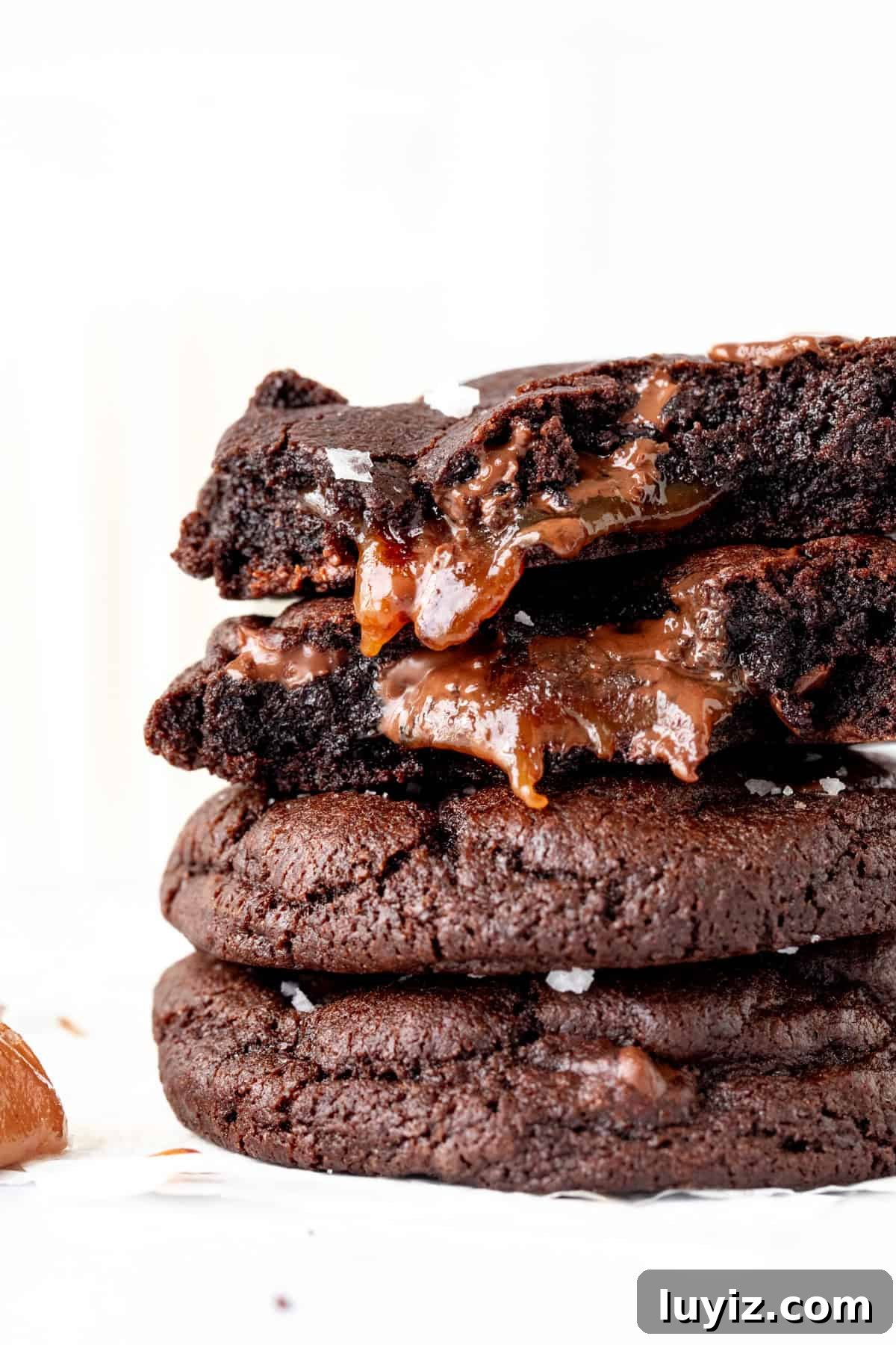 Decadent Dark Chocolate Caramel Cookies — Chewy, Gooey Treats 2 Stack of chocolate caramel cookies, with top cookie broken in half and caramel oozing out.