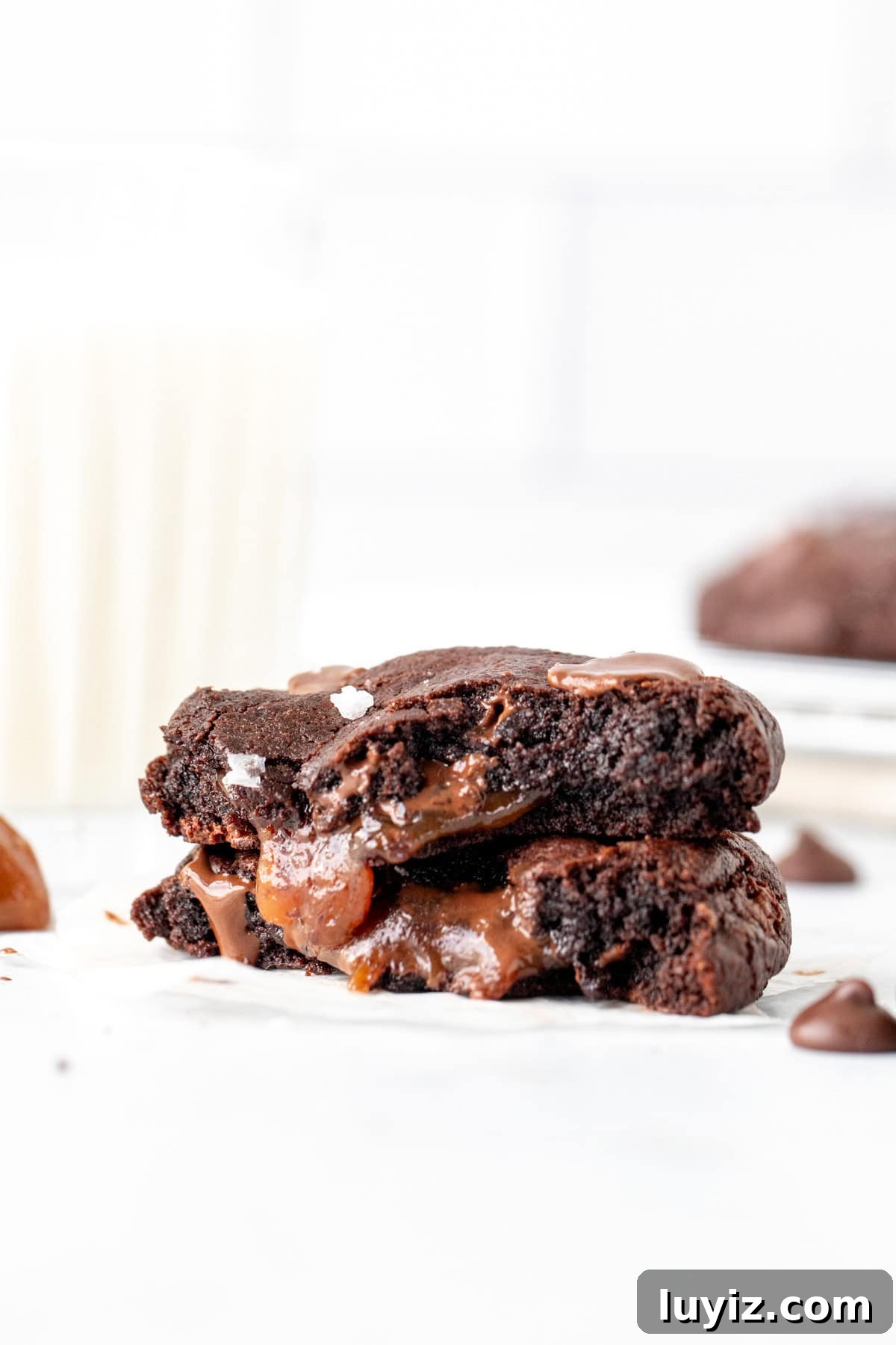Decadent Dark Chocolate Caramel Cookies — Chewy, Gooey Treats 7 Dark chocolate caramel cookie, broken in half with glass of milk