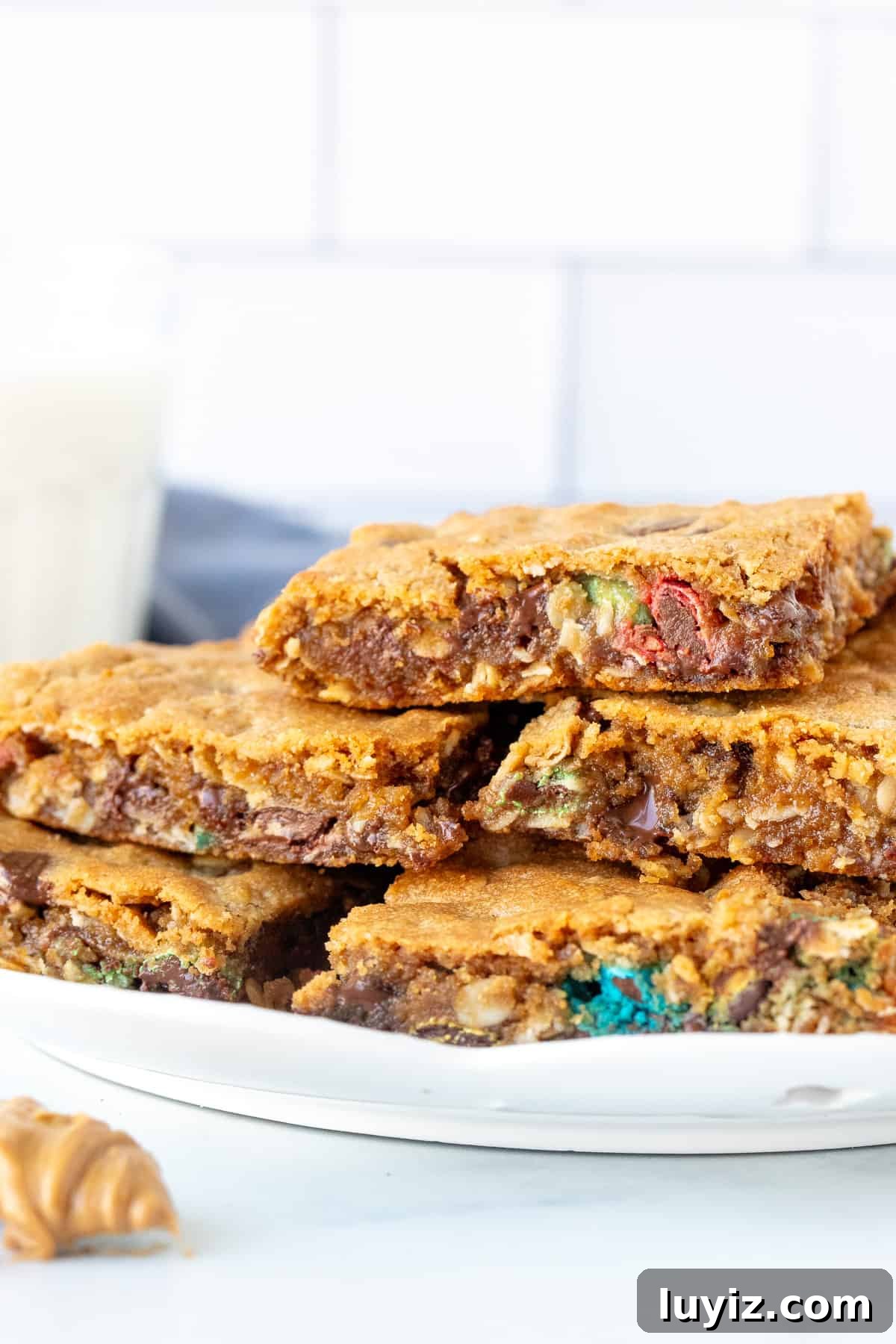 Chewy Monster Cookie Bars Recipe with M&Ms and Oats 3 Plate of gooey peanut butter oatmeal cookie bars, piled on top of each other