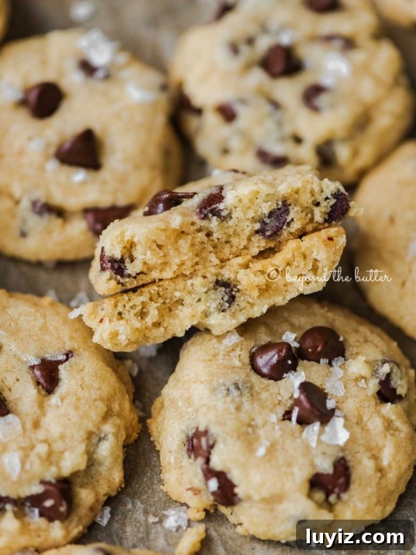 Brown Butter Chocolate Chip Skillet Cookie Recipe 9 Salted chocolate chip shortbread cookies randomly placed on cookie sheet with the center cookie in half to show the middle.