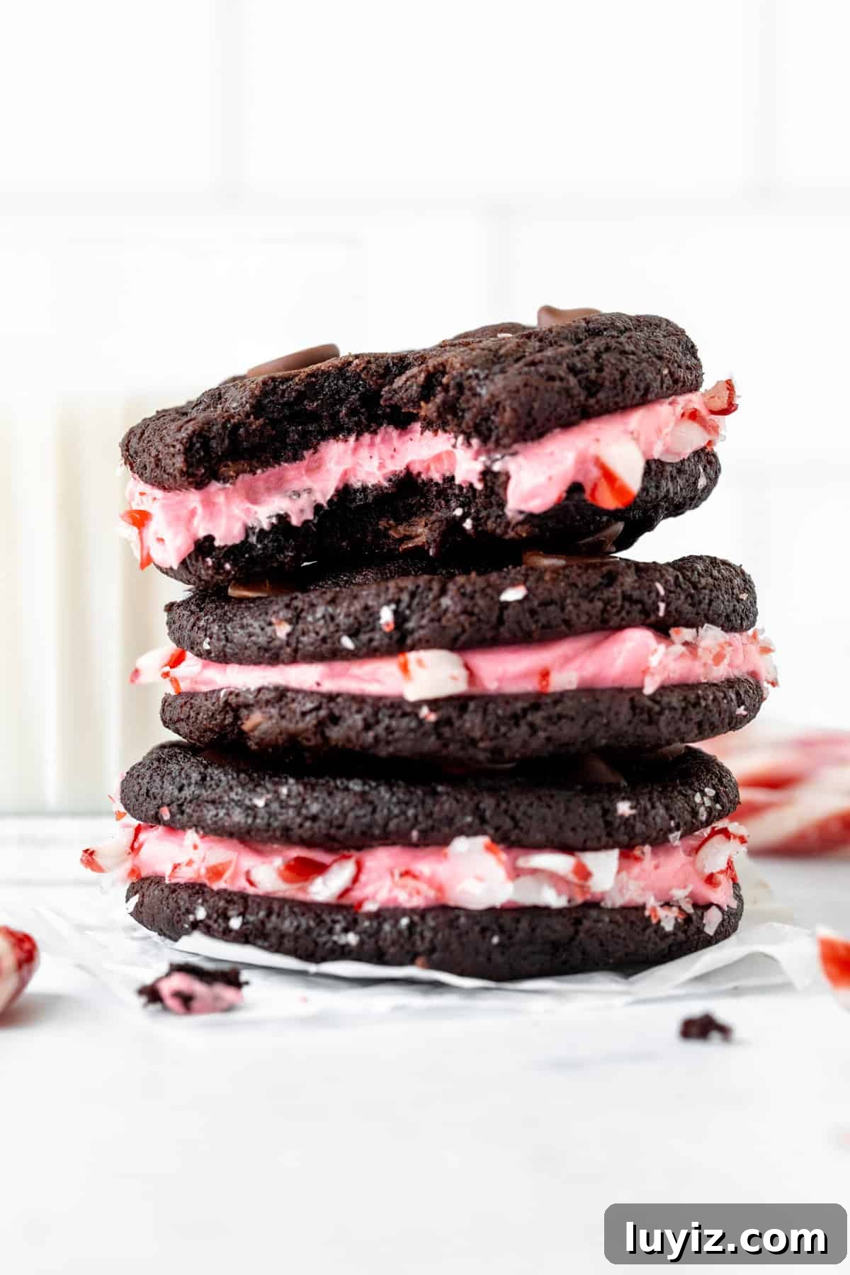 Chocolate Peppermint Sandwich Cookies Recipe 3 Three chocolate candy cane sandwich cookies, stacked on top of each other, with bite taken out of top cookie