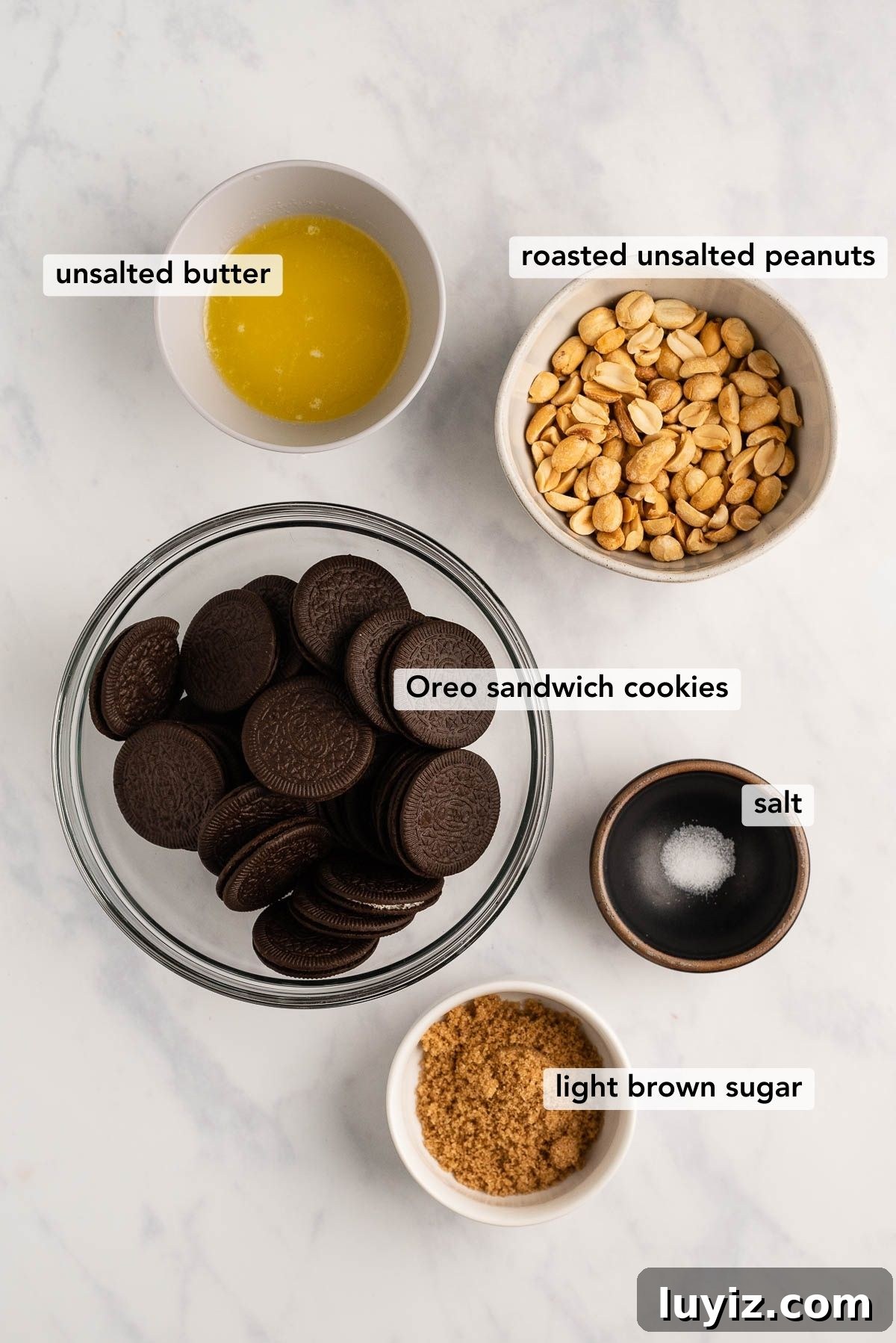 Reese’s Peanut Butter Cup Cheesecake Recipe: Decadent No-Bake Dessert 3 Overhead image of ingredients used to make the oreo cookie crust for a Reese's peanut butter cheesecake on white and grey marble background.