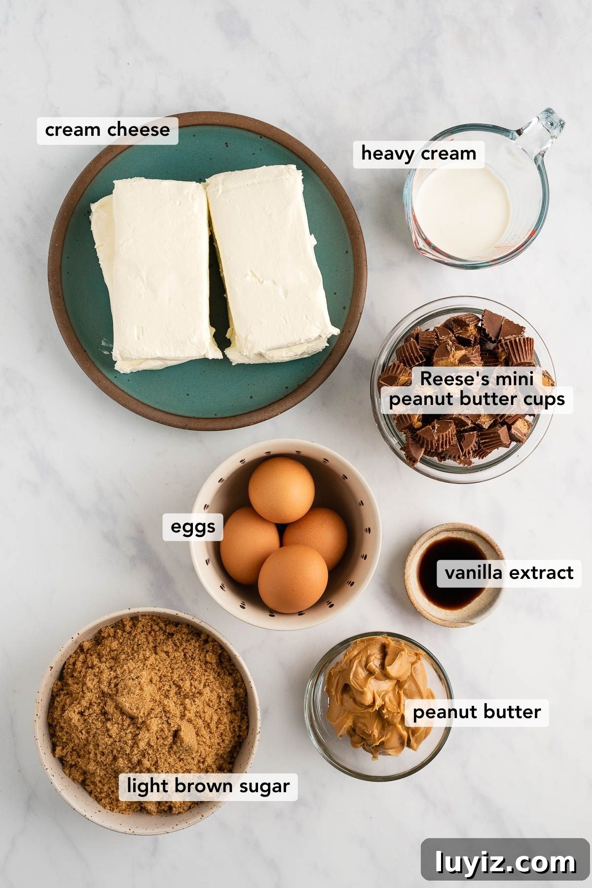 Reese’s Peanut Butter Cup Cheesecake Recipe: Decadent No-Bake Dessert 4 Overhead image of ingredients used to make Reese's peanut butter cup cheesecake on white and grey marble background.