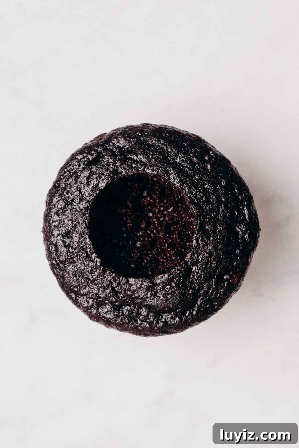 Mint Chocolate Cupcake Recipe: Moist Chocolate Cakes with Minty Frosting 13 One chocolate cupcake with cored out center on a grey marbled background.