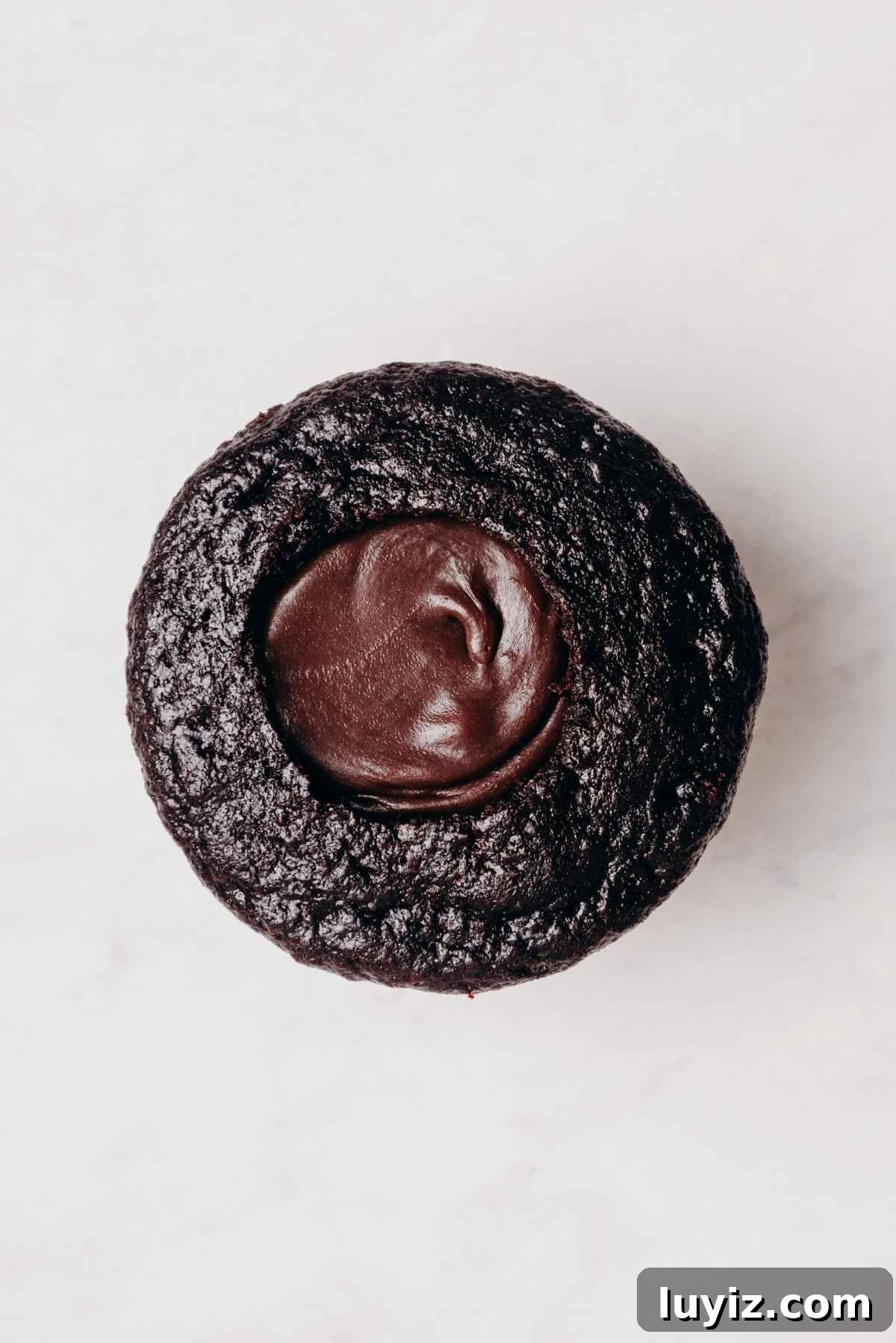 Mint Chocolate Cupcake Recipe: Moist Chocolate Cakes with Minty Frosting 14 One chocolate cupcake with cored out center filled with mint chocolate ganache on a grey marbled background.