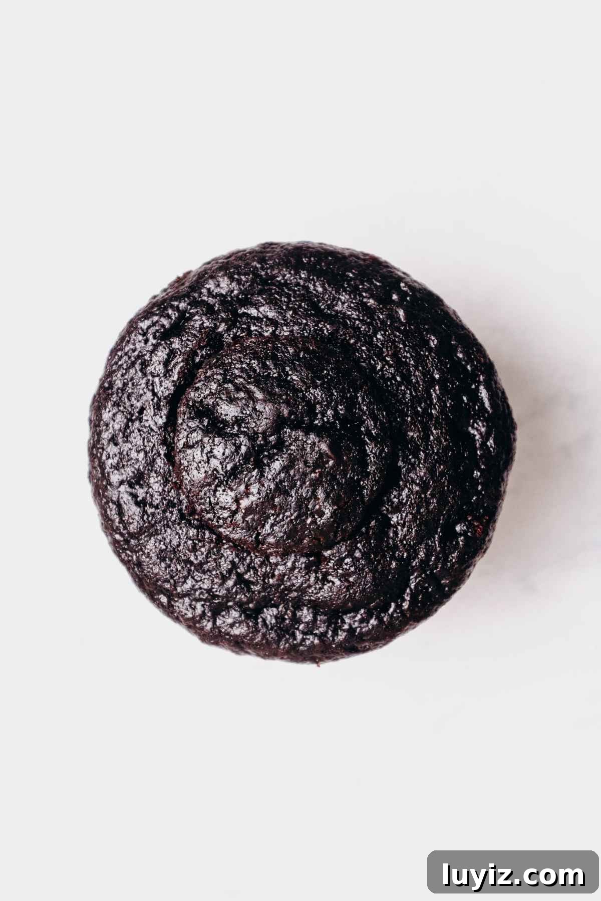 Mint Chocolate Cupcake Recipe: Moist Chocolate Cakes with Minty Frosting 15 One chocolate cupcake filled with mint chocolate ganache topped with round piece of chocolate cupcake on a grey marbled background.