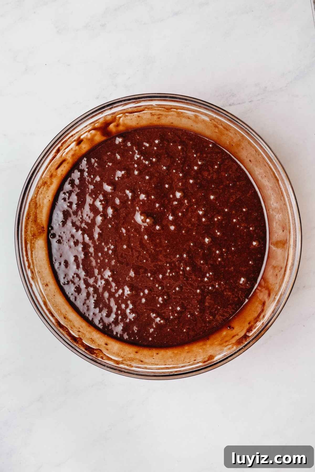 Mint Chocolate Cupcake Recipe: Moist Chocolate Cakes with Minty Frosting 8 Chocolate cupcake batter fully blended in a medium size glass mixing bowl on a grey marbled background.