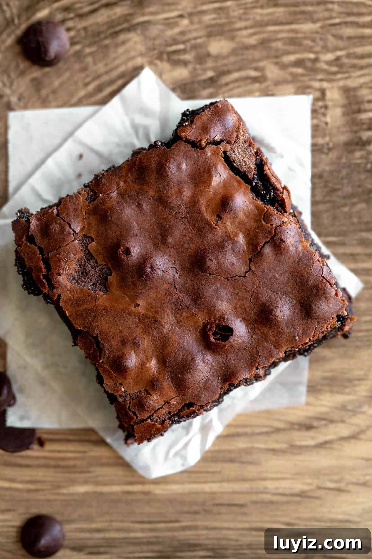 Chewy Fudgy Homemade Brownies Made with Cocoa 8 Brownie with crinkly top on a square of parchment paper