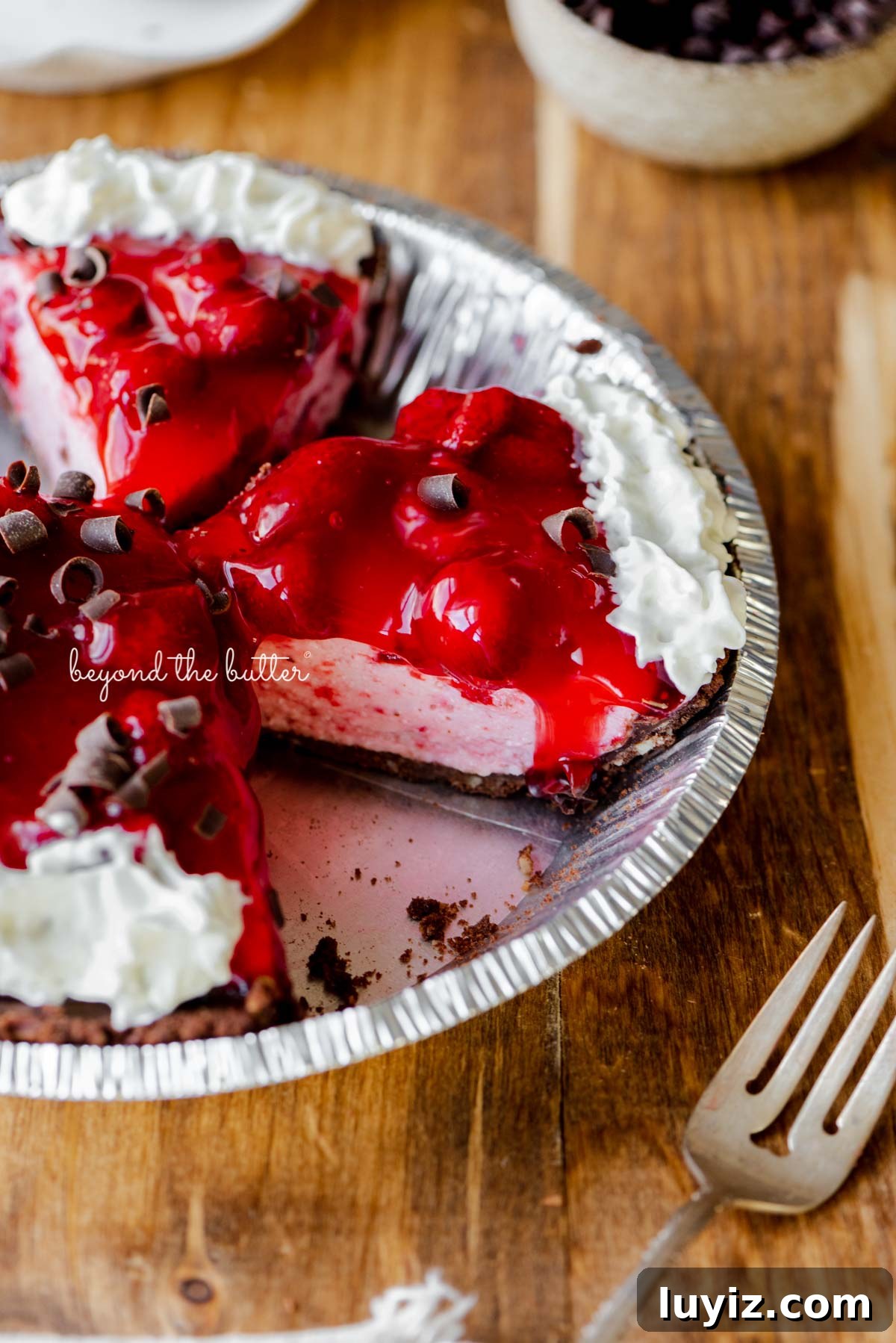 No-Bake Chocolate Strawberry Pie Recipe for Summer Parties 6 Sliced no bake strawberry chocolate cream pie on wood table with a fork and small bowl of chocolate curls nearby | All images © Beyond the Butter®
