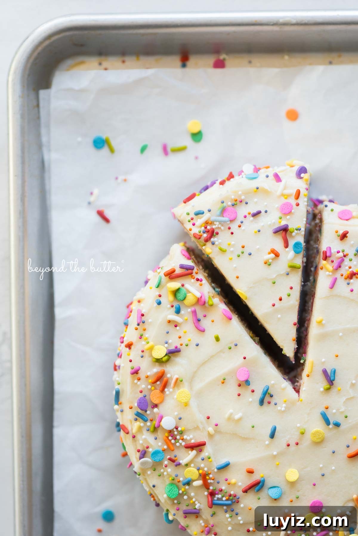 Single-Layer Funfetti Cake Recipe: Quick Party Dessert 11 Cut slice of single layer funfetti cake partially removed from rest of the cake on a parchment paper lined baking sheet | All images © Beyond the Butter®