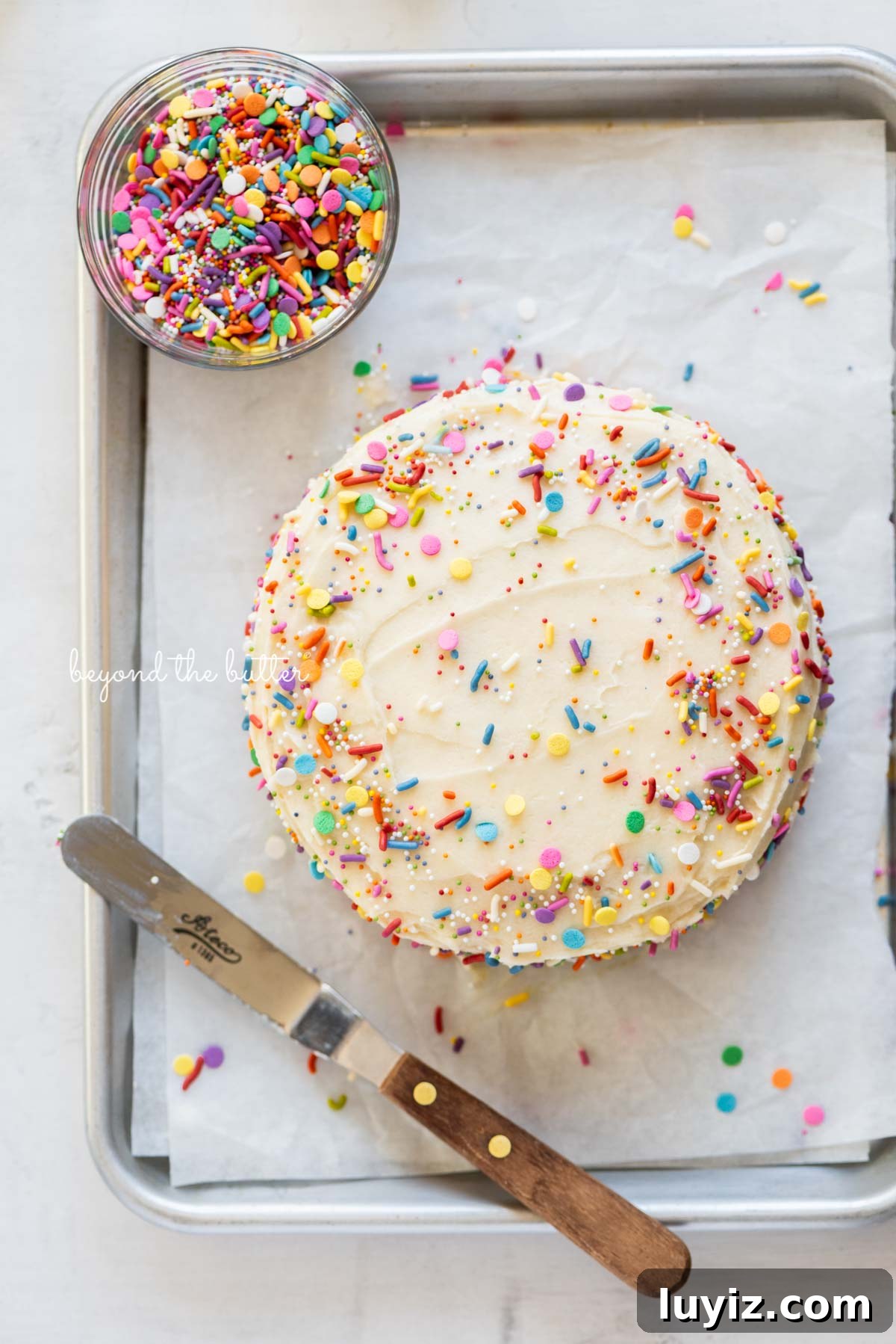 Single-Layer Funfetti Cake Recipe: Quick Party Dessert 4 Single layer funfetti cake just frosted and sprinkled on a small parchment paper lined baking sheet from BeyondtheButter.com | All images © Beyond the Butter®