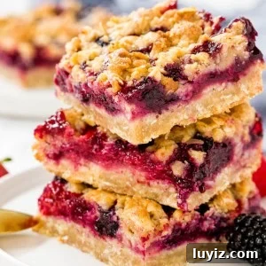Mixed Berry Crumble Bars Recipe — Quick Fruit Dessert Bars 6 3 berry crumble bars made with oatmeal and brown sugar stacked on a white plate.