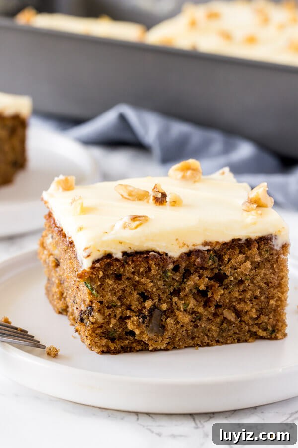 Moist Zucchini Cake Recipe with Cinnamon and Walnuts 4 A side angle shot of moist, tender zucchini cake with cream cheese frosting and topped with a few chopped walnuts.
