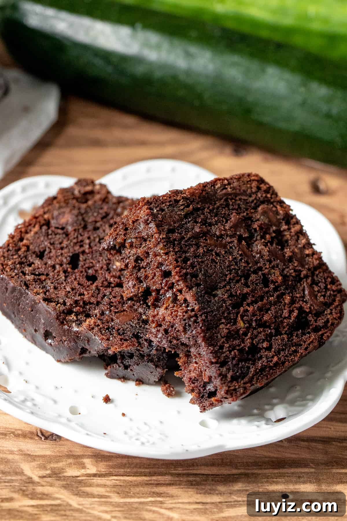 Moist Chocolate Zucchini Bread Recipe with Dark Cocoa 7 Slice of chocolate zucchini loaf broken in half on a plate.