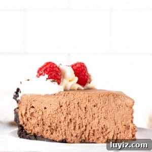 Creamy No-Bake Chocolate Cheesecake Recipe 11 Slice of no bake chocolate cheesecake with whipped cream and raspberries around the edges