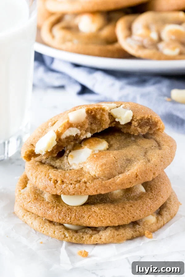 White Chocolate Macadamia Nut Cookies Recipe 5 A stack of subway copycat white chocolate macadamia cookies with the top cookie broken in half to show the chewy center.