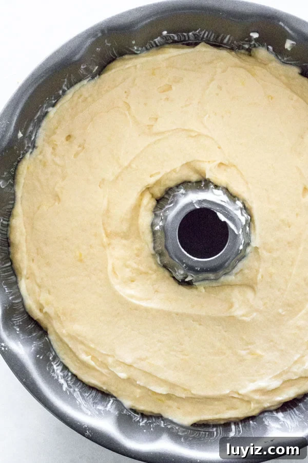Zesty Lemon Bundt Cake Recipe with Glaze 5 Overhead shot of lemon Bundt Cake batter spooned into a fluted bundt pan, and spread smooth on top.