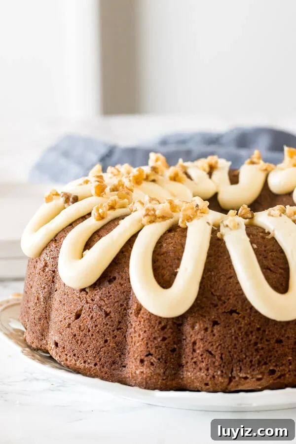 Moist banana bundt cake with a drizzle of thick cream cheese icing on top and sprinkled with walnuts.