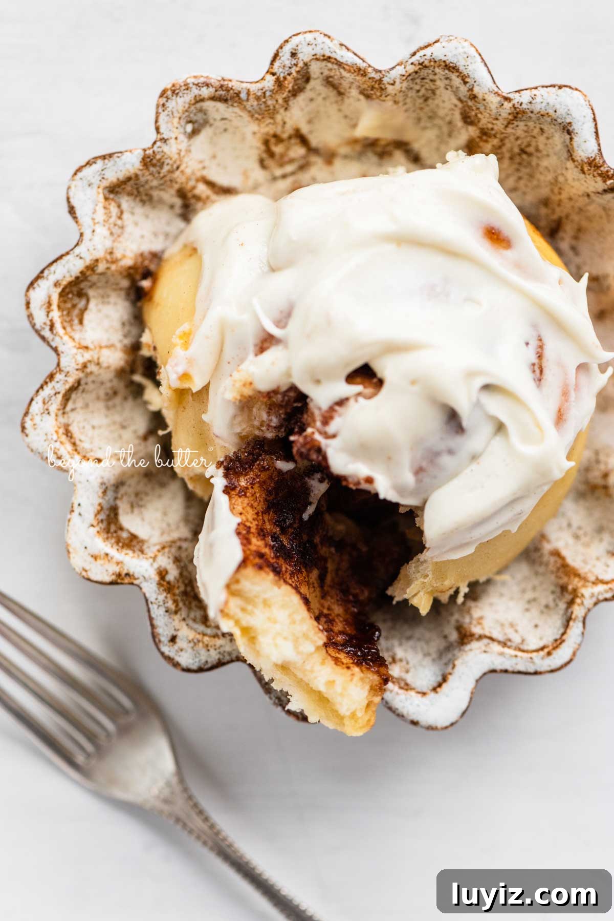 Small-Batch Cinnamon Rolls Recipe for Two to Four People 4 Cream Cheese frosting covered cinnamon roll on small ceramic dessert plate | © Beyond the Butter®