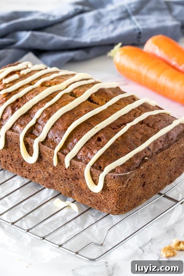 Moist Banana Carrot Quick Bread Recipe 3 Carrot banana bread with a drizzle of cream cheese glaze pictured as the whole loaf on a wire cooling rack.
