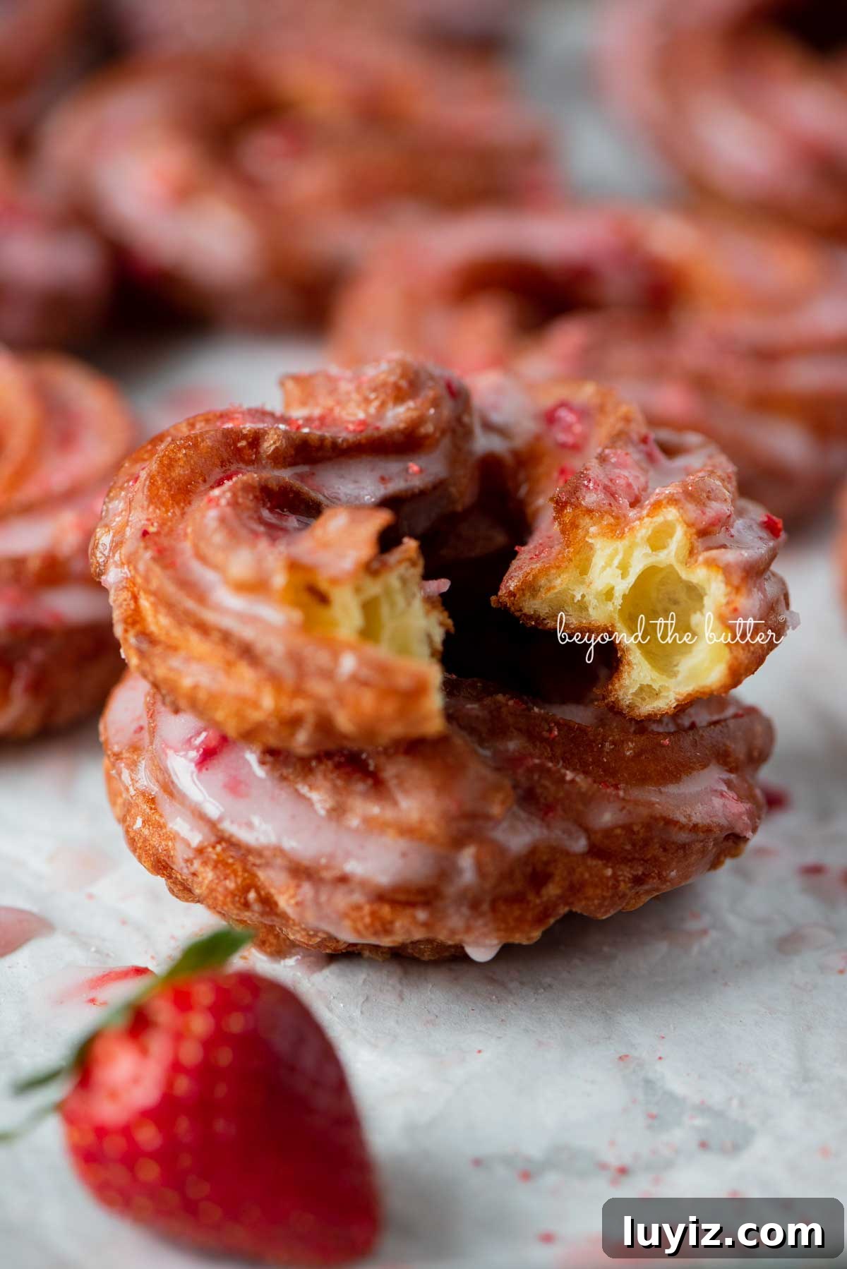 Strawberry-Glazed French Crullers Recipe for Homemade Pastries 4 Light and airy stacked strawberry glazed french crullers with cite taken out of the top cruller | © Beyond the Butter®