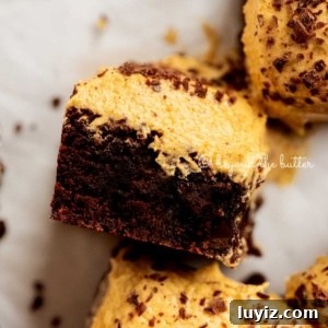 Pumpkin Fudge Brownies with Creamy Frosting 11 Closeup of pumpkin frosted brownie on its side on white parchment paper.