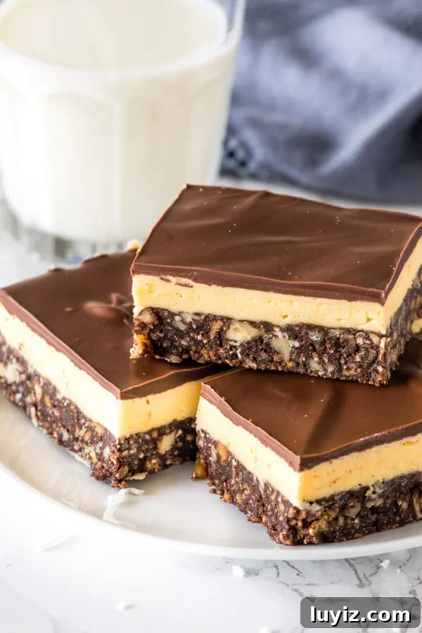 How to Make Classic Nanaimo Bars: No-Bake Canadian Dessert Recipe 2 A plate of classic Nanaimo bars stacked with custard buttercream filling and chocolate on top,