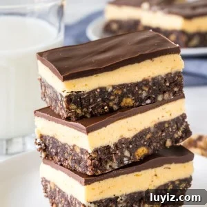 A stack of 3 classic Nanaimo bars on a white plate with a glass of milk in the background.
