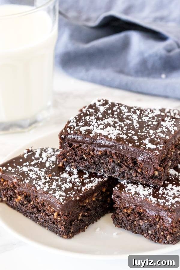 Decadent Chocolate Slice Recipe for Perfect Dessert Moments 3 A plate of 3 pieces of chocolate coconut slice with a chewy chocolate base, fudgy chocolate icing and dessicated coconut on top.