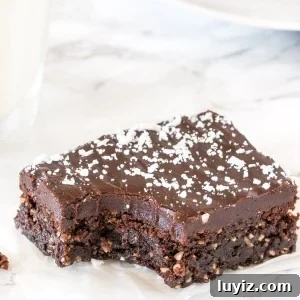 Close up of a piece of chocolate coconut slice with a bite taken out of it to show the fudgy, chewy texture.