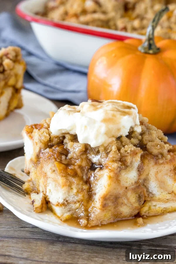 A slice of pumpkin french toast bake with a bite taken out of it as whipped cream and maple syrup drizzle down the sides.