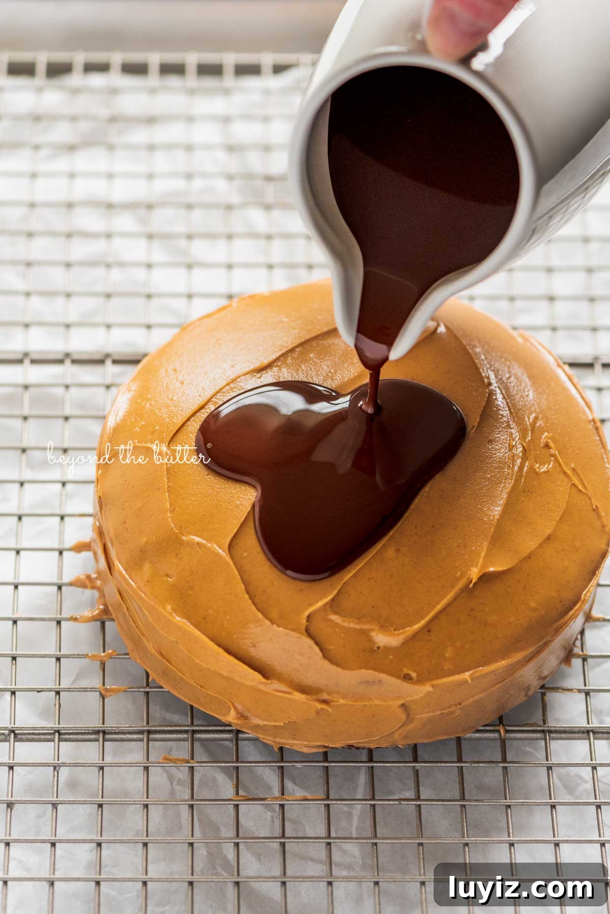 Mini Chocolate Peanut Butter Tandy Cake Recipe 5 Pouring the melted chocolate over top of the peanut butter layered tandy kake on a wire cooling rack baking sheet | © Beyond the Butter®