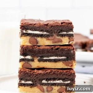 Decadent Fudgy Brownies with Gooey Cookie Layer 5 Stack of three layered brownies on a plate