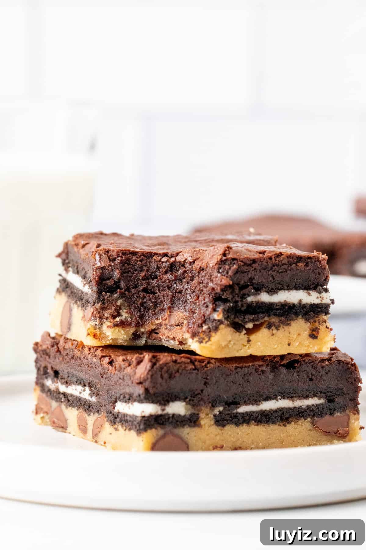 Decadent Fudgy Brownies with Gooey Cookie Layer 4 Two layered cookie-Oreo-brownie bars stacked with a bite taken out