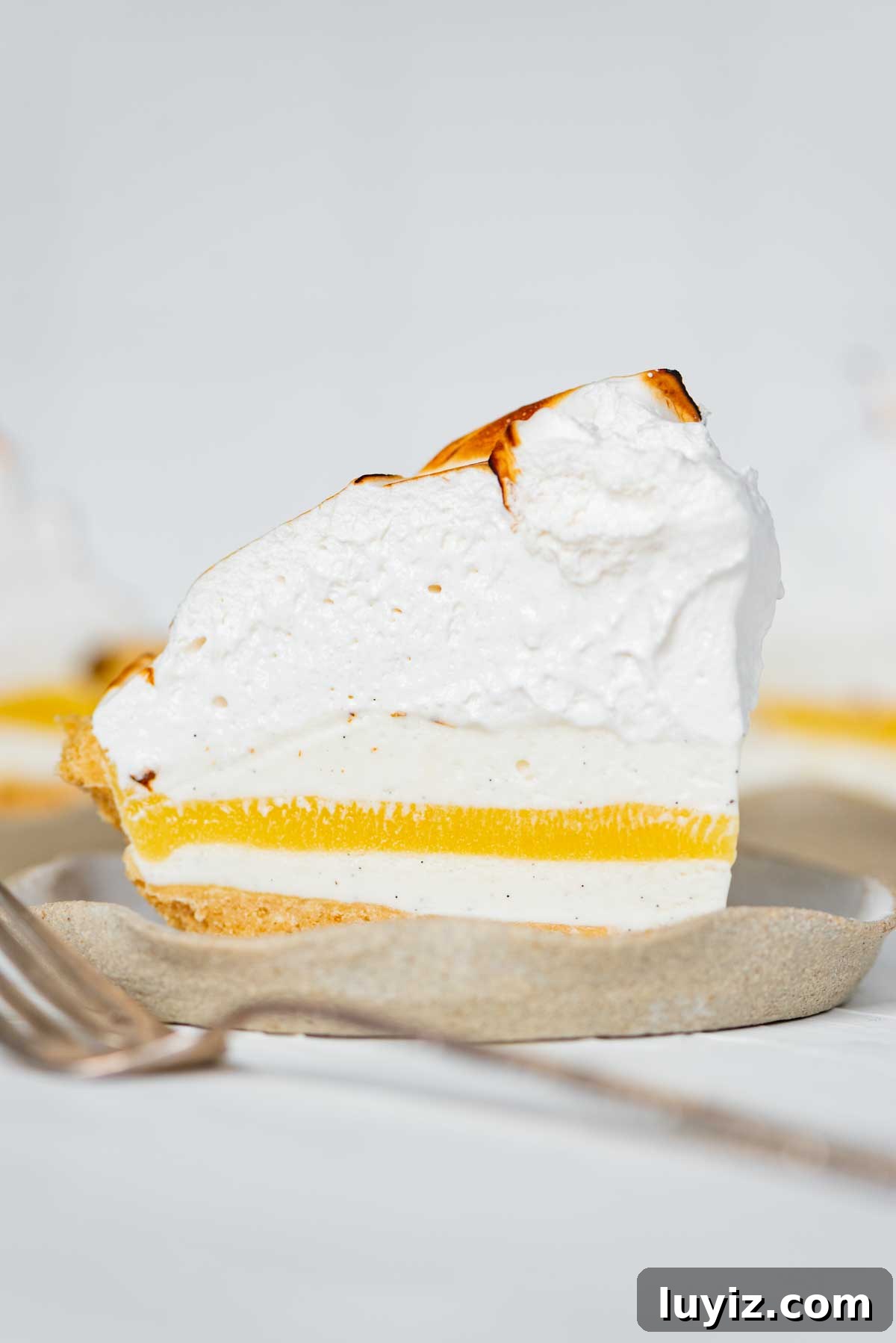 Lemon Meringue Ice Cream Pie Recipe — No-Bake Citrus Dessert 3 Slices of lemon meringue ice cream pie on dessert plates from BeyondtheButter.com | © Beyond the Butter®