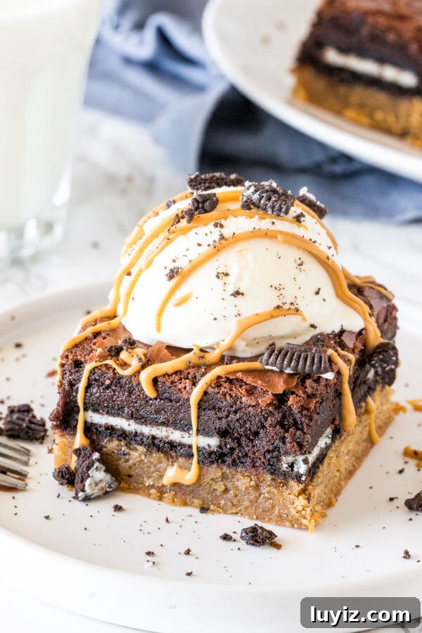 Decadent Peanut Butter Brownies with Oreo Swirls 4 A peanut butter slutty brownie with a scoop of ice cream and drizzled peanut butter on top.
