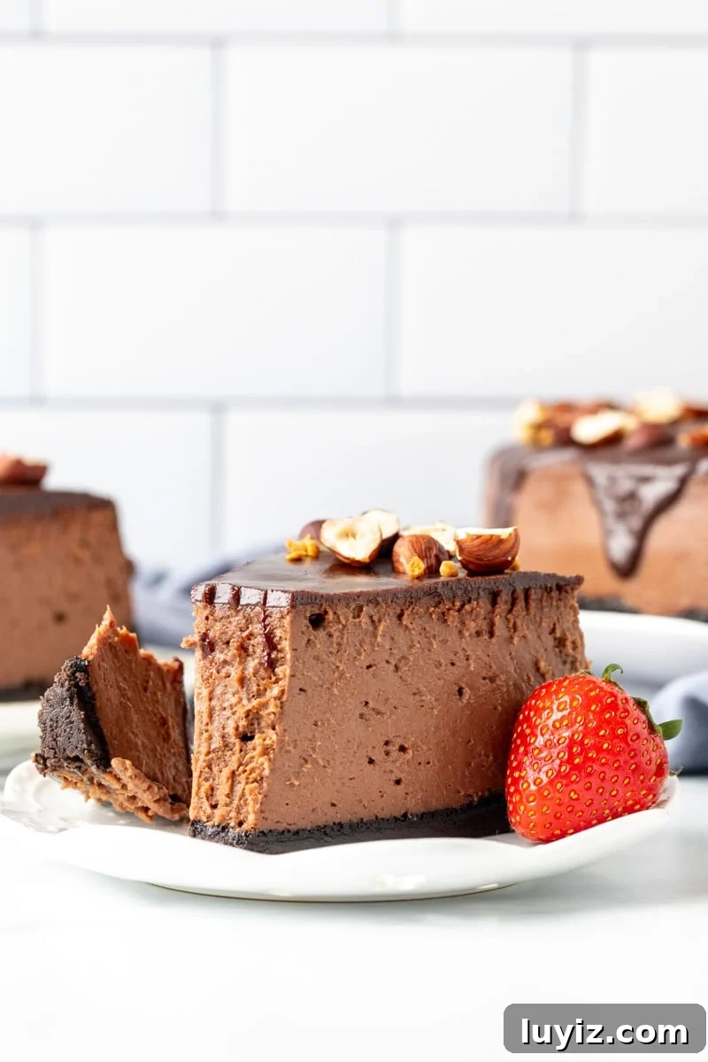 Decadent Nutella Cheesecake with Oreo Cookie Crust 9 Slice of Nutella cheesecake with bite taken out on a plate with a strawberry