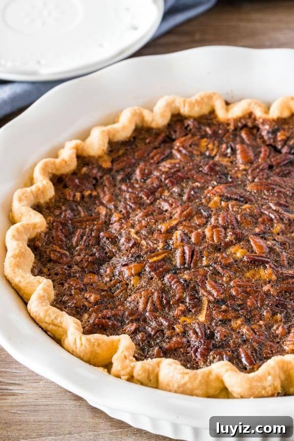 Classic Southern Pecan Pie Recipe with Buttery Pecan Topping 5 Baked pecan pie in a white pie dish fresh from the oven.