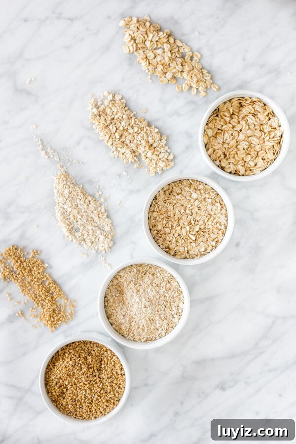 Delicious Oat-Based Baking Recipes for Every Occasion 3 Old-fashioned oats, quick oats, instant oats and steel cut oats displayed top to bottom on a marble surface.