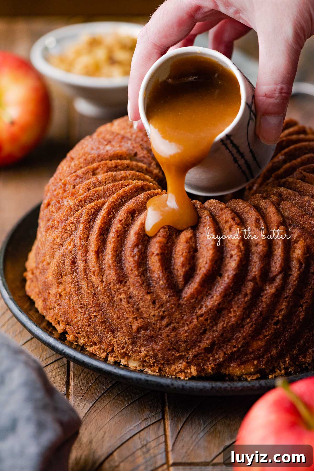 Moist Apple Bundt Cake with Cinnamon Glaze 4 Pouring brown sugar glaze over top of warm apple bundt cake | © Beyond the Butter®