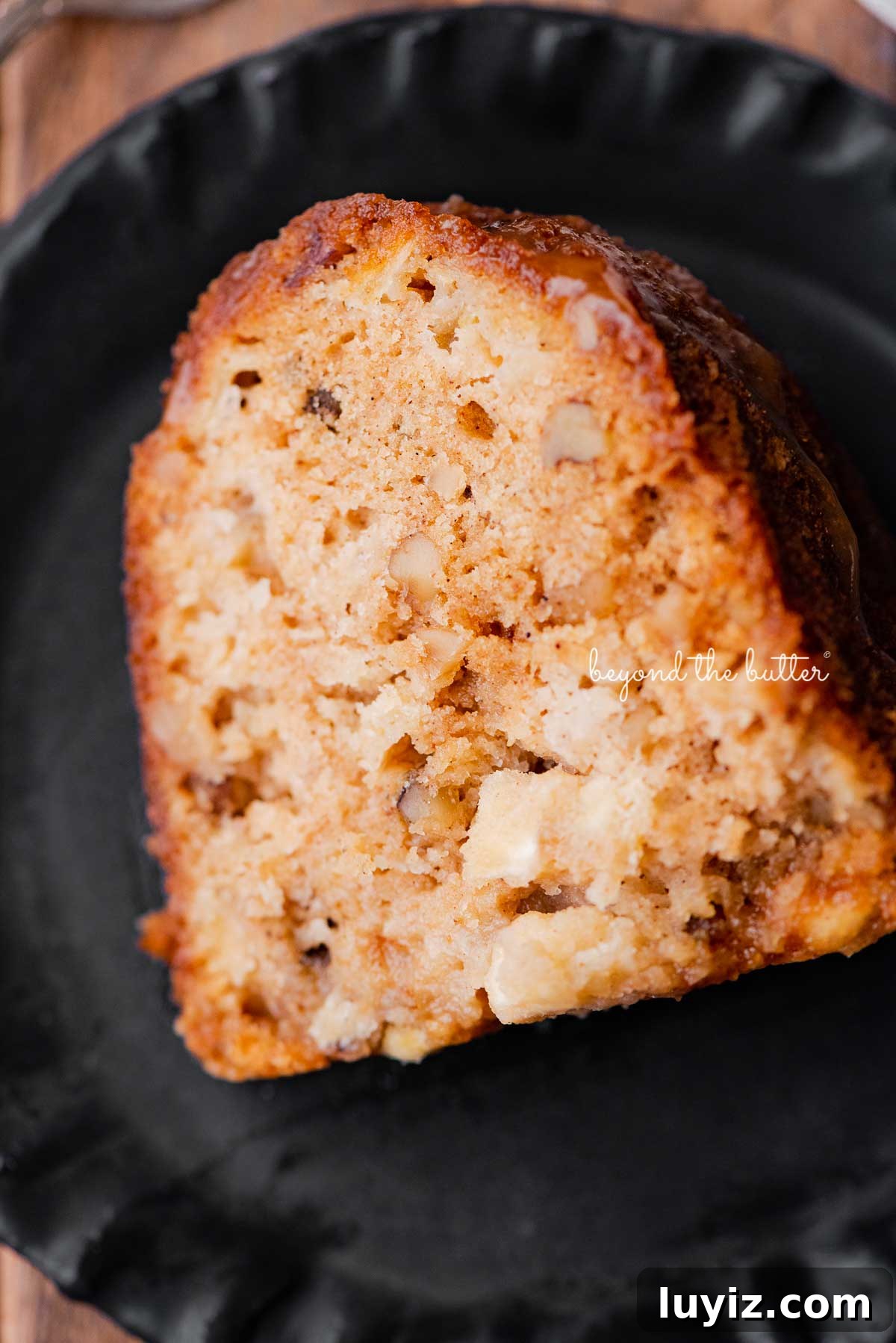 Moist Apple Bundt Cake with Cinnamon Glaze 8 Slice of homemade apple bundt cake on dark wood background | © Beyond the Butter®