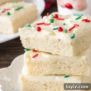 A stack of 3 Christmas sugar cookie bars on a white plate taken from the side.